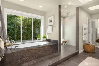 Soaking tub with garden window, step-in shower with glass tile surround.