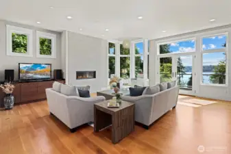 Sunlit living room with expansive Marvin windows that capture the shimmering water views
