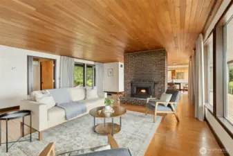 Floor to ceiling windows frame the beautiful views.   Maple floors and wood ceilings in the living room and dining room add warmth and detailing.  Beautiful brick fireplace.
