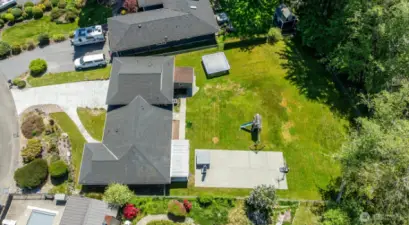 Large backyard with basketball, hot tub, shed, and play set.