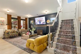 The fully remodeled staircase is a showstopper, featuring oak treads custom-stained to blend seamlessly with the flooring below. Elegant black metal balusters and wood handrails add a modern touch, while the newly installed vintage-style runner with decorative brass rods brings warmth and character. Floor-to-ceiling trim work adds architectural interest as the stairs lead to the upper level, where the luxury vinyl plank flooring continues for a cohesive, high-end finish throughout.