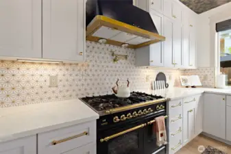 This gourmet kitchen is anchored by a showstopping ILVE 36-inch Nostalgie dual fuel range, featuring five sealed brass burners and a 3 cu. ft. oven—all wrapped in rich black and gold detailing for timeless European flair. Above, the ILVE Majestic range hood offers 600 CFM of power with a built-in anti-grease filter, four fan speeds, warming lights, and an auto-off function—blending performance and luxury. The marble mosaic backsplash, finished with shimmering gold grout, adds a layer of texture and elegance, perfectly tying together the space’s refined palette and thoughtful design.