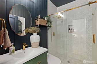 Just steps from the main-level bedroom, this fully remodeled ¾ bathroom feels like a boutique hotel retreat. Elegant vertical shiplap walls are paired with a free-standing vanity and brushed gold fixtures for a modern yet timeless look. The walk-in shower features floor-to-ceiling statement tile and a sleek glass enclosure. A smart toilet adds unexpected luxury with a remote-controlled heated seat, auto flush, and both posterior and feminine wash functions—proof that even the most functional spaces can feel indulgent.