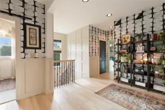 Upstairs, the hallway was thoughtfully expanded and widened to create a more open, gallery-like transition between rooms. Natural light pours in through the large window, enhanced by crisp millwork and striking grid-style wall trim. The bold, removable wallpaper adds a modern design punch without long-term commitment—perfect for those who love to make a statement. It’s a stylish and functional space that elevates even the in-between moments of daily living.