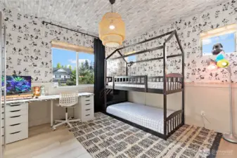 This whimsical bedroom is full of charm and character, featuring classic Disney wallpaper paired with a playful brick wallpapered ceiling for a fun, layered look. Wainscoting adds a touch of architectural detail, while custom wood-stained shelving maximizes storage without sacrificing style. With plenty of natural light and room to play, study, or sleep, this space is equal parts functional and delightful.