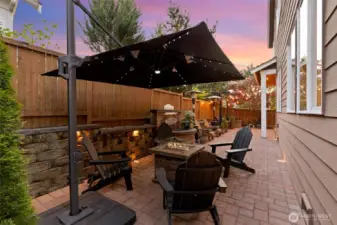 This backyard is fully set for unforgettable evenings—complete with a cozy firepit, ample Adirondack seating, and a large cantilever umbrella with built-in lighting, all of which stay with the home. Whether you're hosting friends or enjoying a quiet night under the stars, the paver patio, integrated lighting, and layered landscaping create a perfectly curated outdoor retreat.
