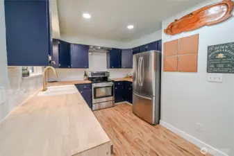 Warm colors in updated kitchen with recessed lighting 4 inch white trim and butcher block counters for all your cooking needs