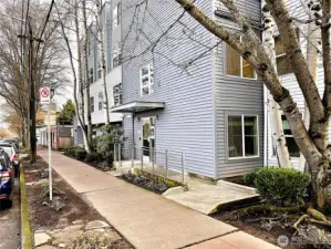 The front entrance is located on Greenwood Ave N and is accessible by this ramp or stairs.  The building has an elevator. The secure garage door is accessed on the northwest side of the building and can be seen in this photo.