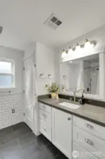 Half tiled wall and quartz counter tops in the primary bathroom.