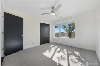 Bedroom 2 -   Spacious secondary bedroom with tree-lined views, sleek ceiling fan, and modern black accent doors for a refined touch.