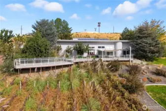 Modern exterior design framed by lush greenery and a wraparound deck — blending contemporary style with natural beauty.