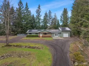 Large gravel driveway with parking pad and additional attached garage with mezzanine space above.