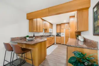 Expansive kitchen with solid wood cabinetry, granite counters, and breakfast bar seating.