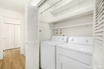 In-unit laundry with full-size washer and dryer plus built-in shelving.