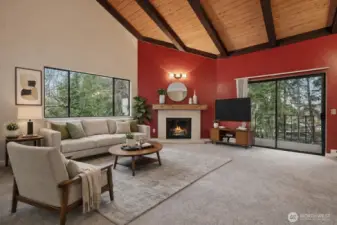 (virtually Staged) Living room with vaulted cedar ceilings, fireplace, large windows, and balcony access.