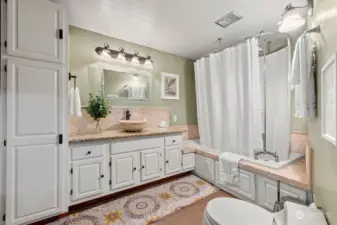 Main level full bath features plenty of custom cabinetry and an oversized jetted tub.