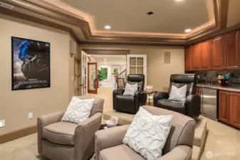 Media Room with kitchenette featuring custom cabinetry, granite counter, and stone backsplash