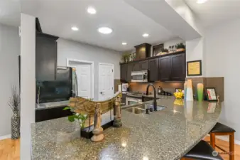 The SolaTube skylights keeps the kitchen light & bright. Rich espresso cabinetry with undermount lighting that accents the full file backsplash and slab granite counters.