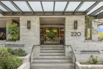 Welcome to 220 1st Street—a grand first impression with this sleek, modern entry. Framed by lush landscaping and contemporary stonework, the covered entrance leads into a secured building with an elegant lobby just beyond the glass doors.
