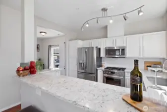 Eating bar with quartz countertop and new lighting and appliances in the backround