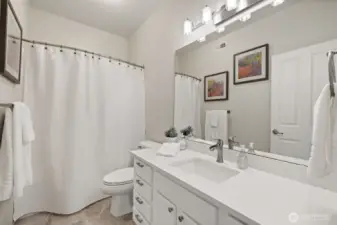 Main bath with newer vanity, quartz counter, new lighting and tile floor
