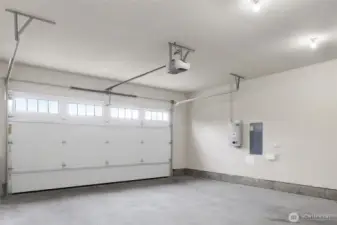 Garage with the solar panel on the wall. There is a door to the side of the home with sidewalk to the driveway.