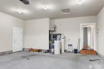 Garage with door to the side yard, and the water filtration system, hot water tank, and the door to the home.