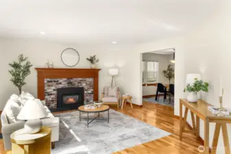 Light-filled and inviting, this spacious living room offers the perfect setting for both everyday living and entertaining. Warm hardwood floors, fresh interior paint, and a classic brick fireplace with a wood mantel create a cozy yet refined atmosphere