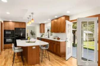 This well-appointed chef's kitchen offers quartz countertops, rich custom cabinetry, and a generous island with bar seating. Thoughtfully designed with a large walk-in pantry and French doors.