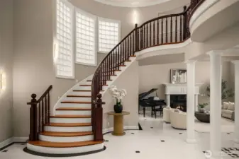 Grand entry foyer with sweeping curved staircase and soaring ceilings.