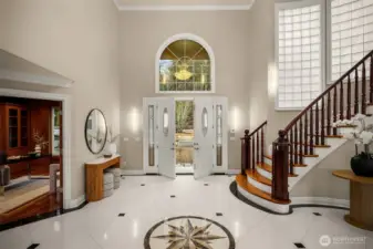 Elegant two-story foyer with sweeping staircase and marble inlay flooring.