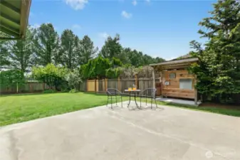 Backyard is private and features a large patio, covered cooking space, and mature landscaping