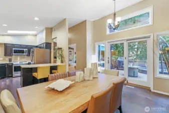 Natural light pours into the dining area through large windows and a transom window above the sliding glass doors, offering direct access to the back deck. This versatile space bridges indoor comfort with outdoor living.