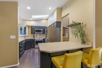 The updated kitchen features quartz counters, painted cabinetry, and stainless steel appliances. A vaulted ceiling with a skylight ensures this space remains light-filled throughout the day.
