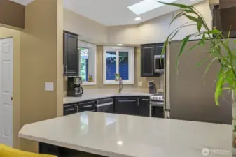 The spacious countertop and breakfast bar serve as a functional extension of the kitchen, perfect for quick meals, entertaining guests, or setting up a snack station during gatherings.