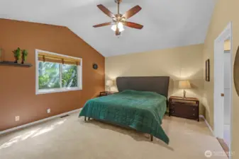 The private primary suite boasts vaulted ceilings, soft new carpet, and garden views from the large window. Its generous proportions offer a restful retreat with easy access to the en-suite bath.