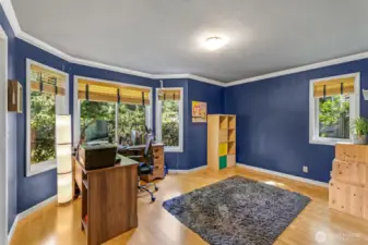 This generously sized secondary bedroom features large windows on multiple walls, bringing in natural light and lush outdoor views. With plenty of space and flexibility, it’s perfect for a home office, guest room, or creative retreat.