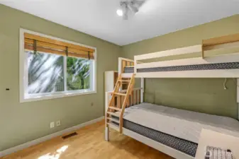The third bedroom overlooks the private backyard and provides a cozy setting for restful sleep or imaginative play. Its warm-toned flooring and ample window make it feel fresh and open.