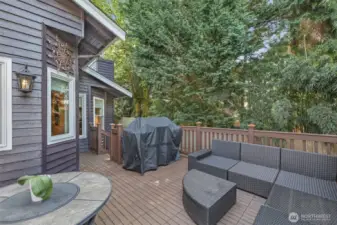 This view showcases the connection between the home’s interior and its deck space, creating an ideal transition for indoor-outdoor gatherings. Towering trees add natural privacy and shade.