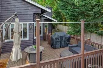 This angle captures the layout of the deck and its direct access to the yard. Surrounded by evergreens, this area offers a tranquil escape ideal for grilling, lounging, or dining al fresco.