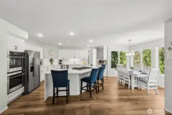 Spacious Kitchen & Dining Combo - this expansive kitchen and dining area offers the perfect setting for large gatherings. Features include a wraparound breakfast bar, high-end appliances, and a sunlit dining space surrounded by oversized windows and backyard greenery.