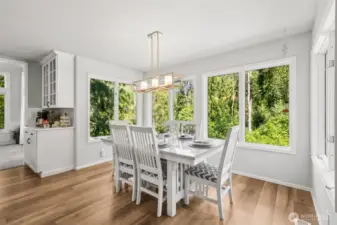 Scenic Breakfast Nook with Tree-Lined Views  Start your mornings in this charming breakfast nook framed by panoramic windows showcasing serene greenbelt views. Features include a stylish modern light fixture, built-in coffee station, and ample space for casual dining.