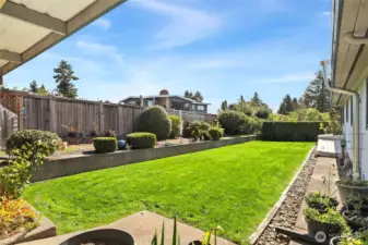 A gardeners delight with a multitude of rhodies, dahlias, and other plantings.  Retaining block walls with arborvitae or fence for privacy 3 sides.