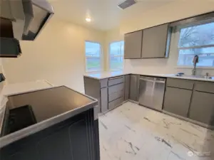 Kitchen with new paint, stove, vent hood, refrigerator, sink, flooring and windows.