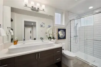 Primary ensuite bathroom with featured trough sink, walk in tiled shower, and built in shelving.