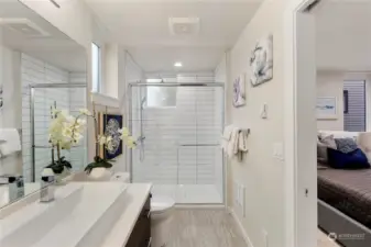 Primary ensuite bathroom with featured trough sink, walk in tiled shower, and built in shelving.