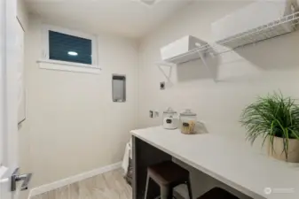 Walk in Laundry room features quartz-topped counters and additional storage area both underneath and above.  Space for a Full size stacking washer and dryer area, and natural light and tiled floors complete this room.