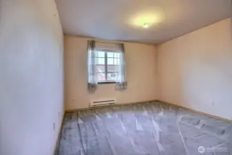 A well-sized third bedroom featuring ample natural light, a new baseboard heater and overlooks the front entry of the house.