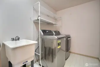 The large laundry room is conveniently located on the upper level and features a utility tub sink for those extra clean-ups and shelving unit which stays.