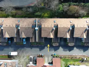 This aerial shot looks down upon the backyard area where mature trees and soft mossy green space create a quiet, park-like sanctuary right behind your home.